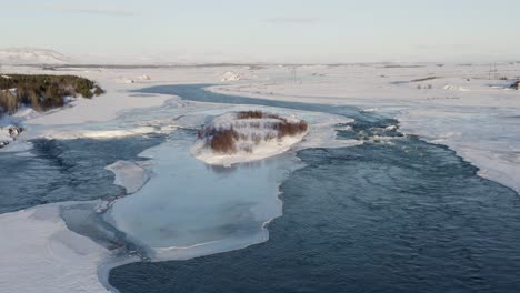 aerial view of olfusa river in iceland flowing slowly between frozen ice and snow layers after strong snowfall