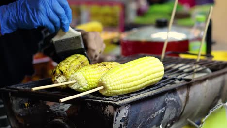 vendor grilling corn with seasoning at night market