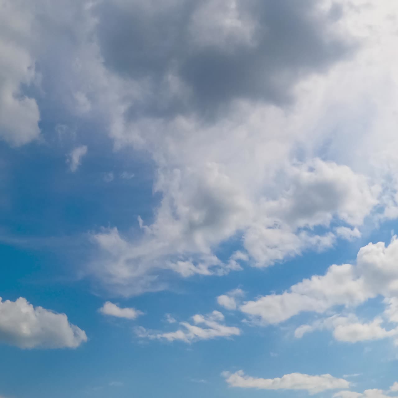 Blue summer sky with light soft clouds. Soft white cloudscape lit by the bright sun. Timelapse