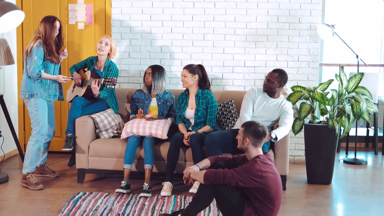 jóvenes amigos felices en un apartamento común tocando la guitarra y cantando