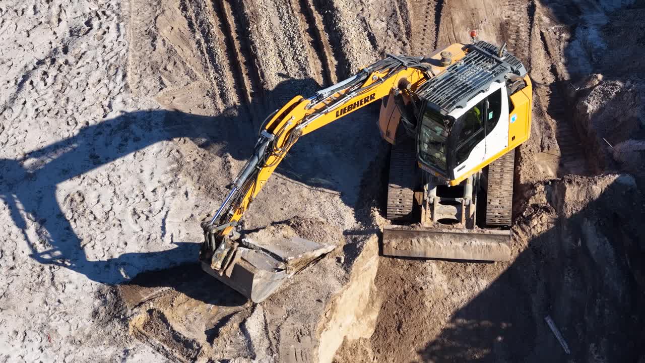 Yellow excavator operates in sunlight, digging and relocating soil at Gold Coast construction site