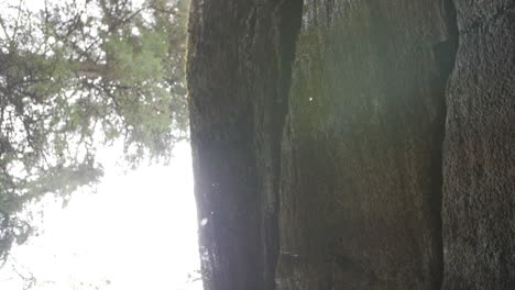 water drops from huge rock mountain in forest to the lens, slow motion