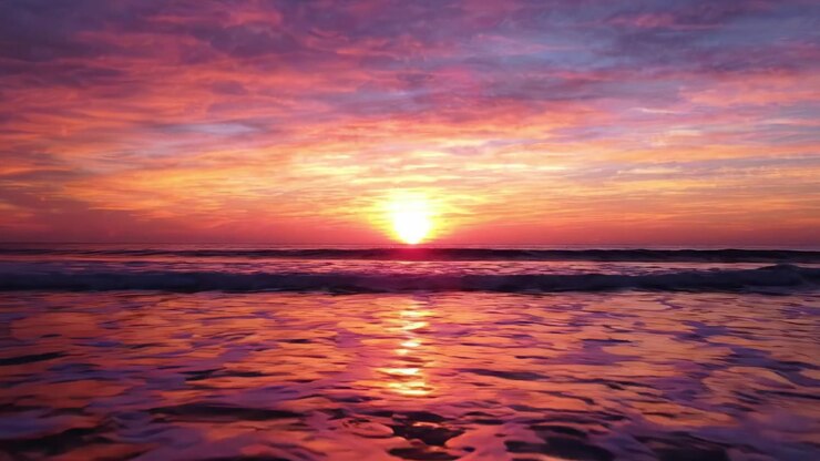 A Stunning Sunset Over the Ocean: Capturing the Vibrant Colors and Tranquil Waves as Day Transitions into Night at the Water's Edge