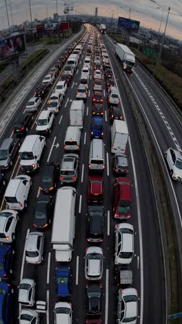 aerial video view of a busy highway during rush hour, capturing rows of cars under a cloudy sky