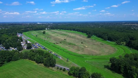 horse gallop racecourse near a forest in germany, parking lot visible. magic aerial view flight fly push forward drone
