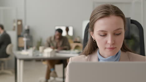 close up view of woman using laptop sitting at table in the office 1