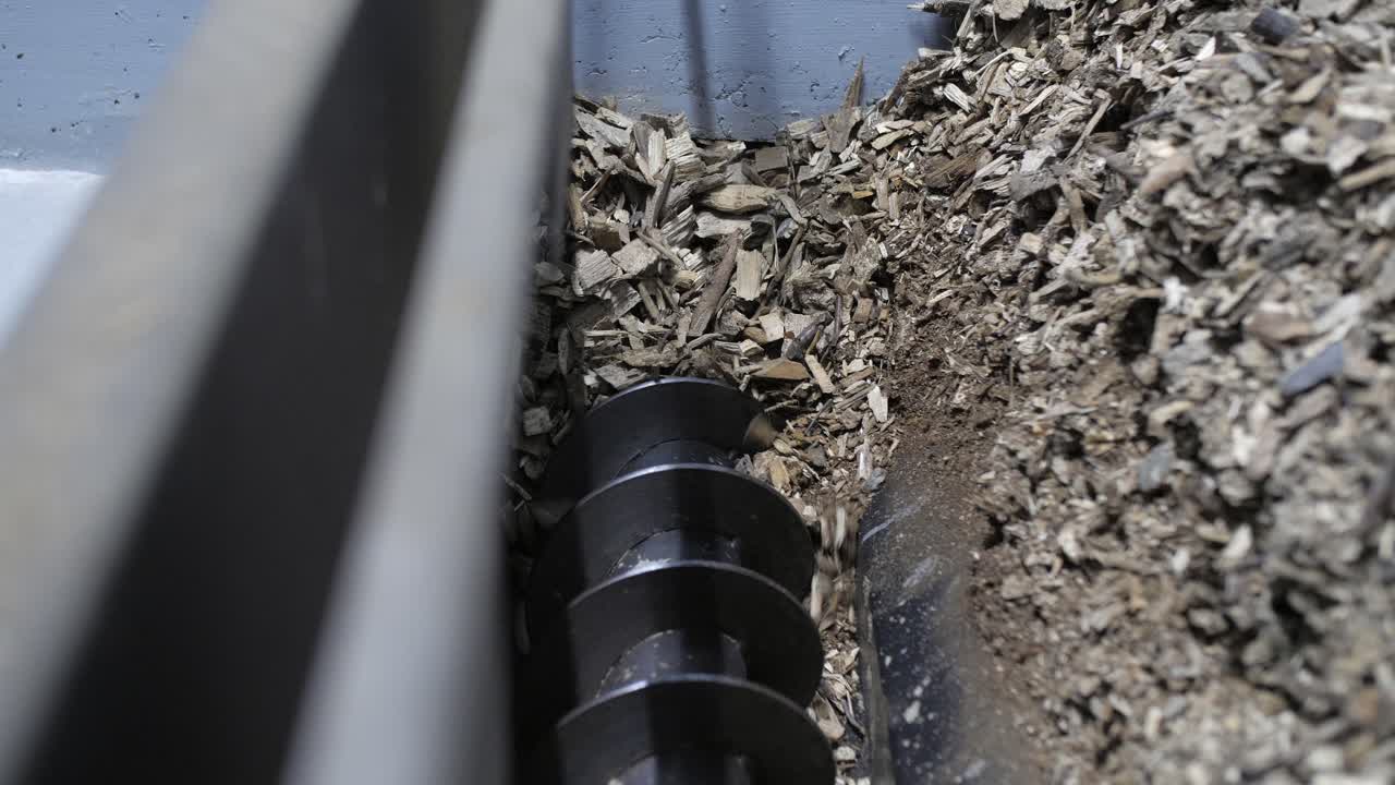 trucioli di legno in una tramoggia che si spostano in una caldaia che brucia biomassa, rallentatore
