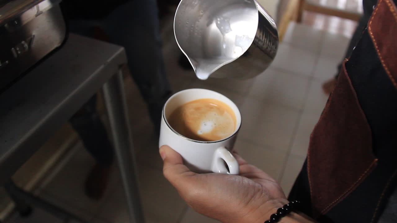 Close up of a barista's hand making a coffee latte. professional coffee making process