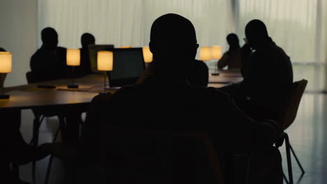 silhouettes of people at a conference table in a dimly lit room