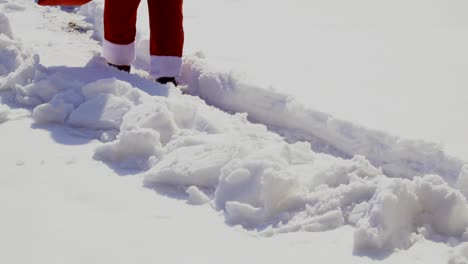 santa claus with bag walk along snow path