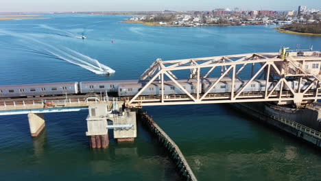 an aerial shot of nyc subway trains cross over the bay in queens, ny