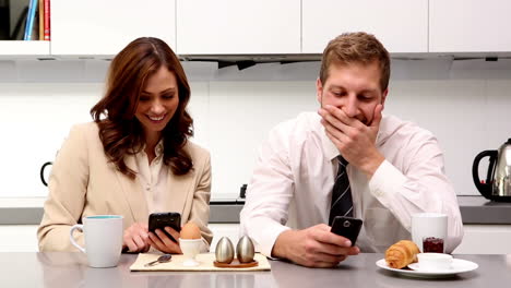 couple showing each other their phones at breakfast