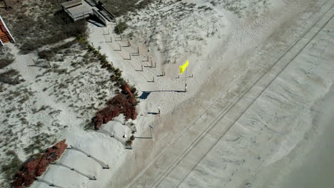 toma de avión no tripulado de la bandera amarilla volando en la playa, toma aérea