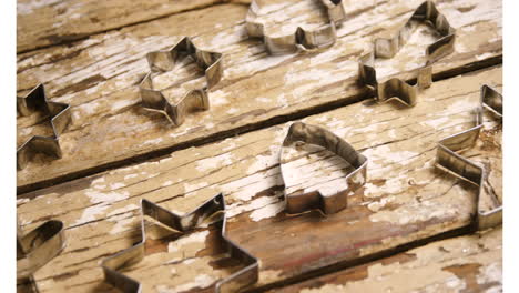 animation of cookie cutters on wooden background at christmas