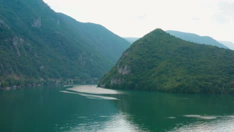 breathtaking view of turquoise water surrounding mountains in lake perucac serbia - aerial drone shot