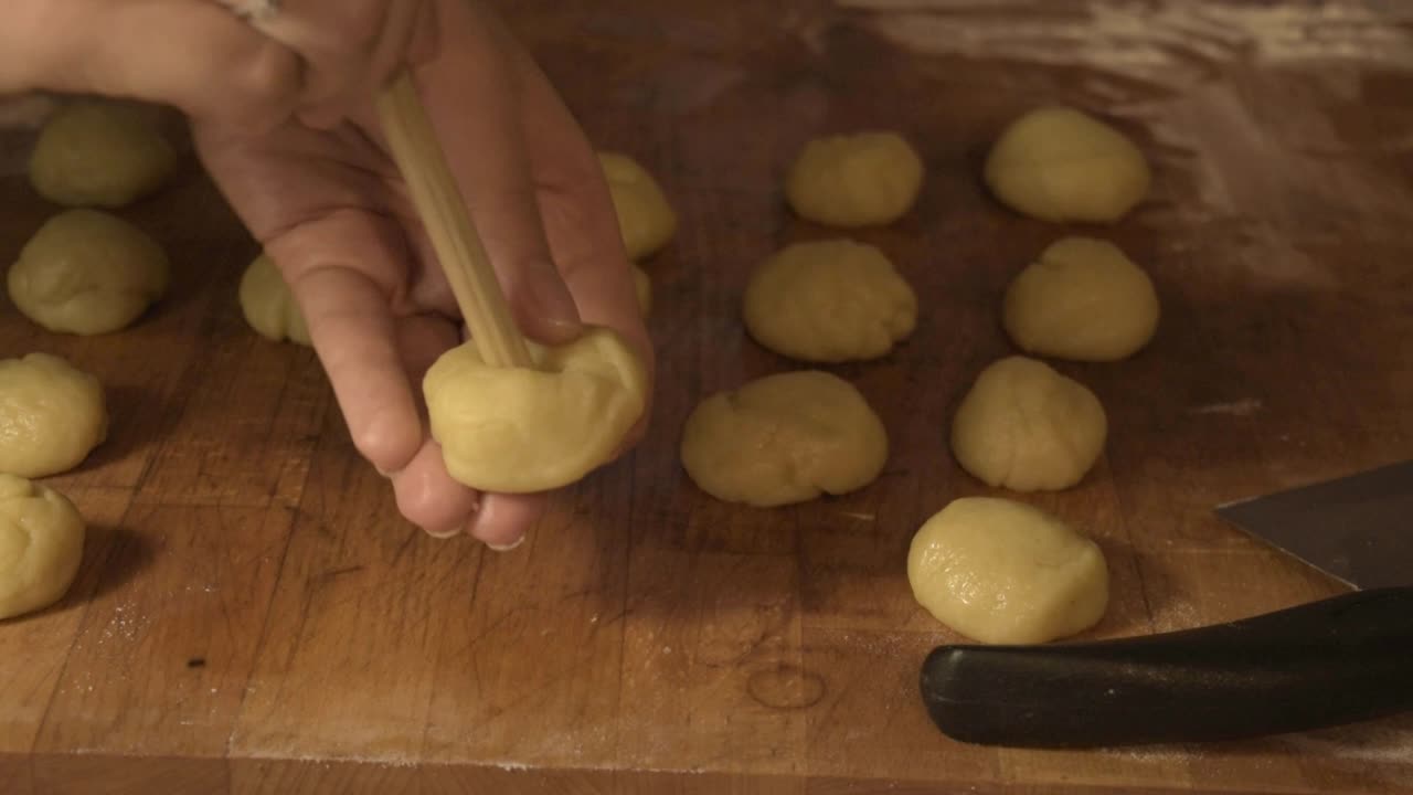 haciendo agujeros con la cuchara de madera en las bolas de masa para galletas, en la tabla de cortar