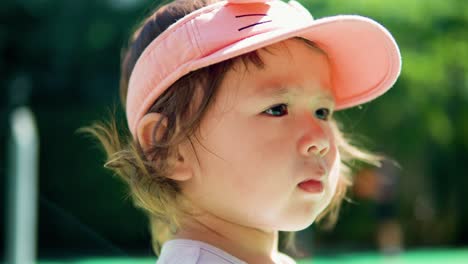 Retrato-De-Una-Niña-Pequeña-Con-Sombrero-Deportivo-Abierto-Mirando-A-Un-Lado-Cuando-Su-Pelo-Rizado-Sopla-En-El-Viento---Cara-De-Cerca-A-Cámara-Lenta