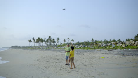 boys flying a drone in beach side