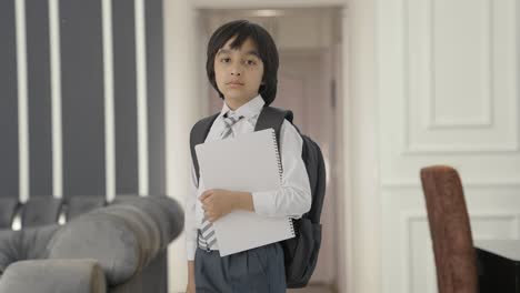 retrato de un niño de escuela indio confiado de pie con libros