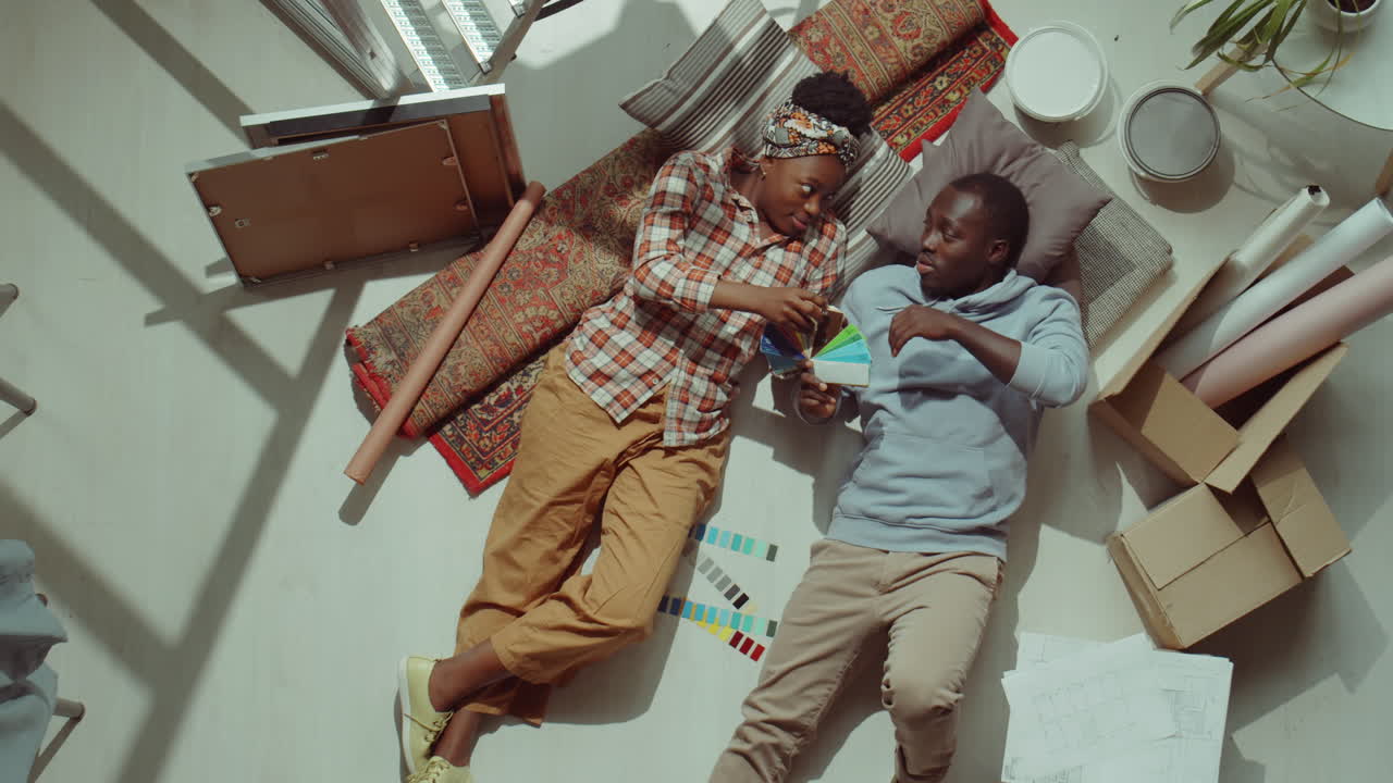 pareja afroamericana discutiendo la paleta de colores mientras renueva la casa