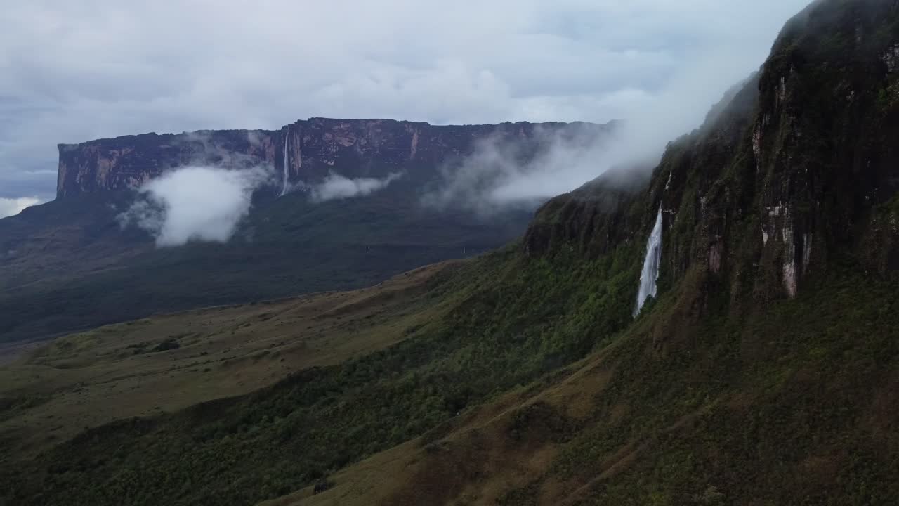vista aérea de parte de la pared de roraima tepuy con una cascada y kukena tepuy en el fondo