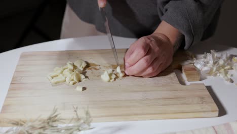 Weibliche-Hände-Schneiden-Knoblauch-Auf-Einem-Holzbrett---Nahaufnahme