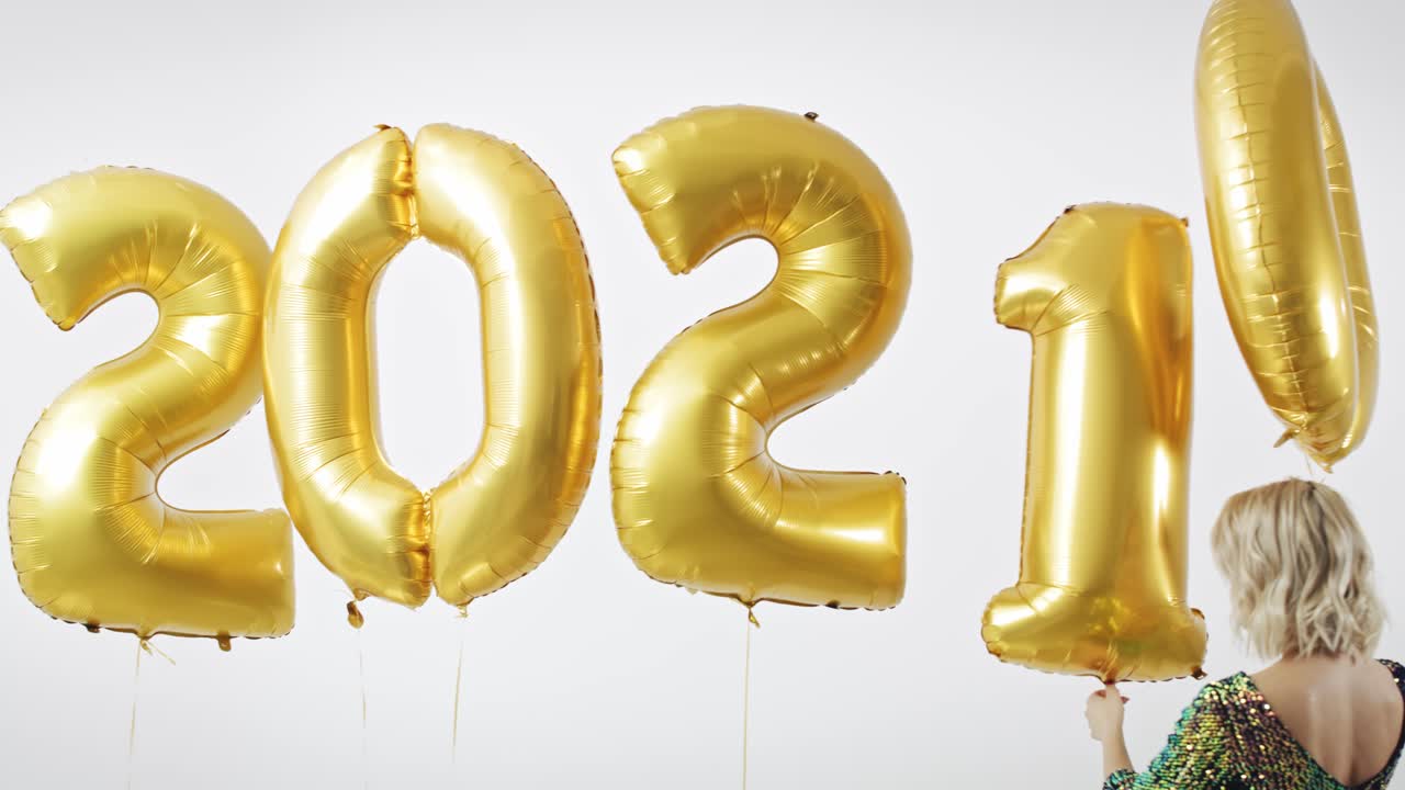 Frau mit goldenen Ballons, die die Zahl „2021“ formt