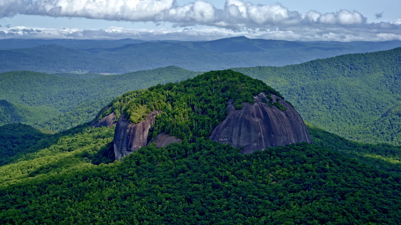Cinematic aerial view of a single large mountain rising independently from the ridgeline