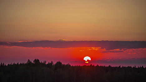 el sol se esconde debajo de las nubes y el bosque al atardecer.