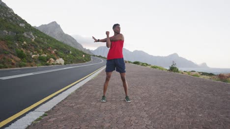 african american man performing stretching his arms while standing on the road