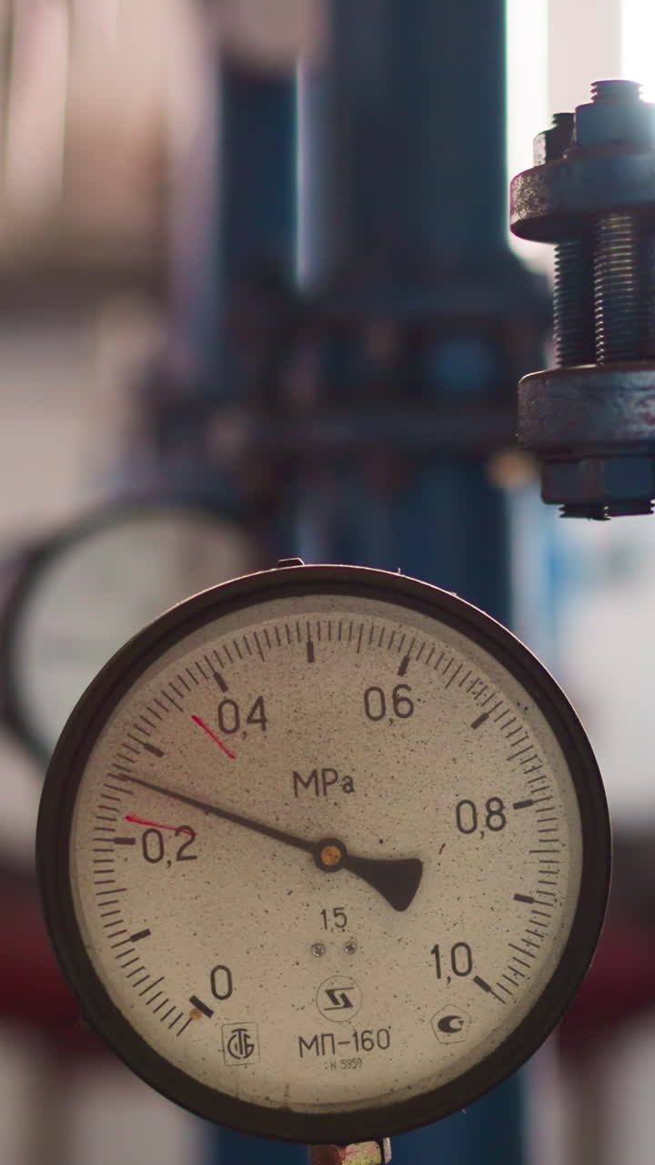 Pressure meter with twitching arrow on hot steam pipe at boiler house closeup. Equipment generates heat for building warming and temperature maintenance