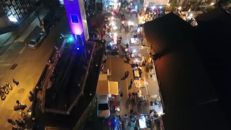 imágenes aéreas de la torre del reloj conmemorativa vietnamita en la provincia de nakhon phanom, tailandia, rodeada de una animada calle peatonal nocturna