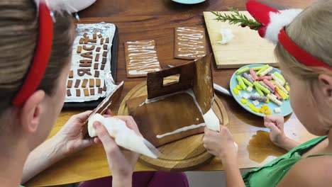 mother and daughter decorating a gingerbread house