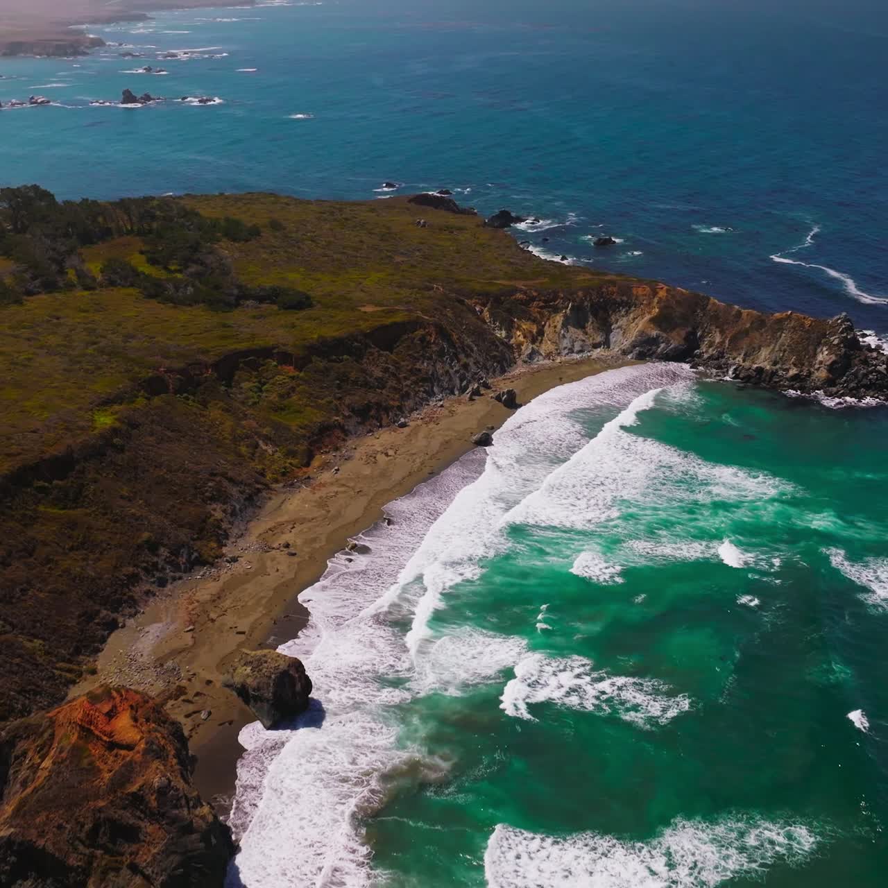 Sunny scenery of Morro Bay rocky coastline at daytime. Low white waves coming to the narrow line of a sandy beach. Top view
