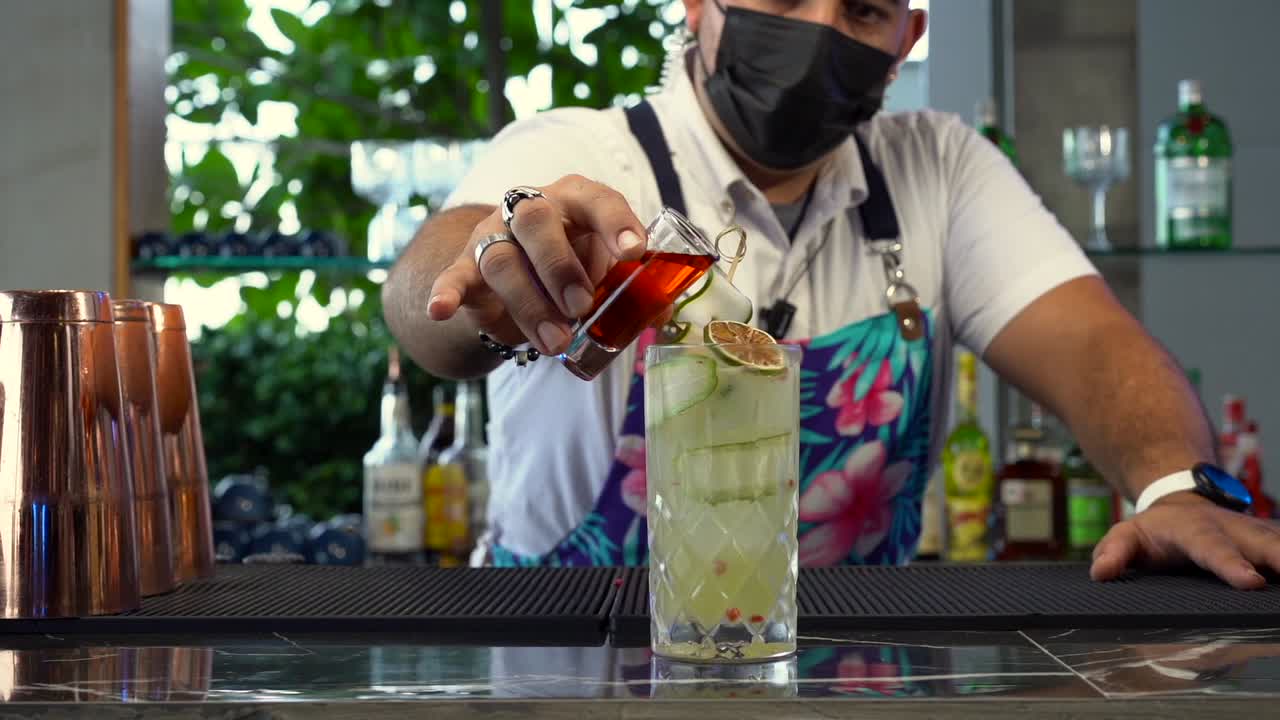 Latin mexican bartender mixology mix red shot of cocktail drink mojito tequila sunrise mezcal lemon gin slow motion at beach restaurant bar