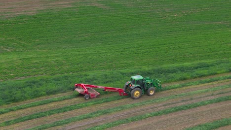 circles of agriculture: aerial glimpse of a green tractor mowing hay in british columbia