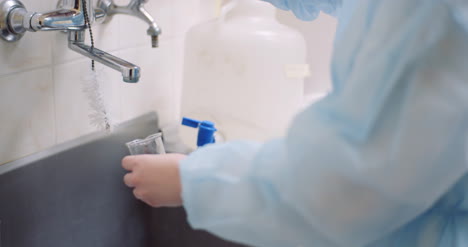 Midsection-Of-Scientist-Washing-Glass-Beaker-At-Sink-In-Laboratory