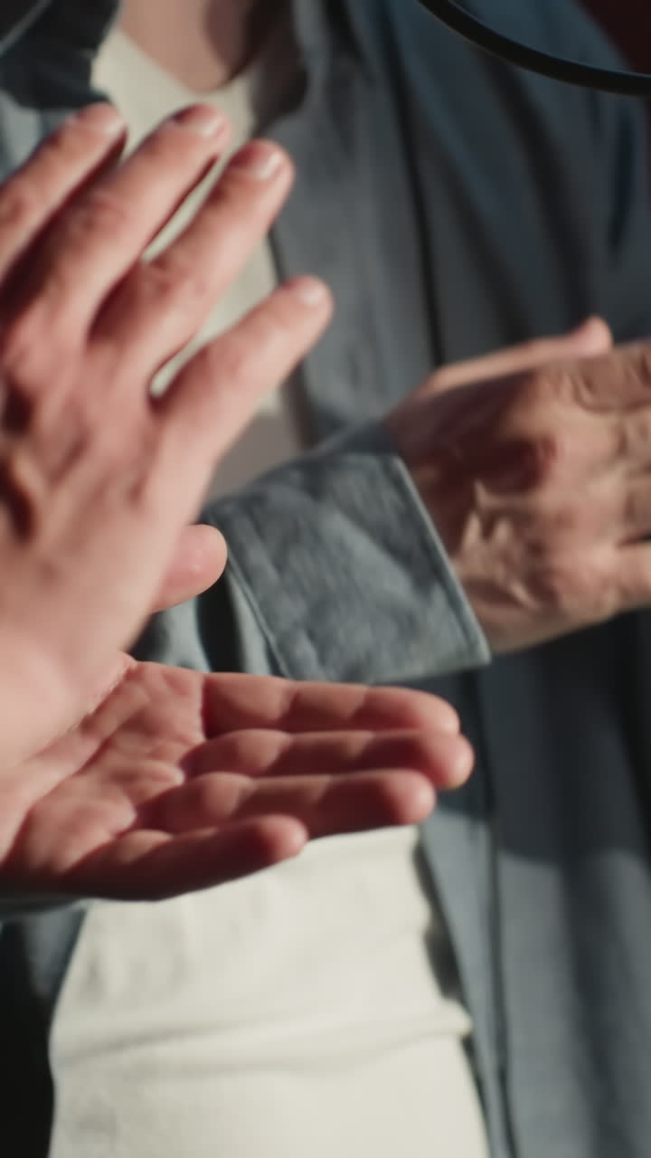 primer plano de dos personas aplaudiendo expresivamente en un estudio de grabación a prueba de sonido, a mitad de actuación frente a un soporte de micrófono. el enfoque está en sus movimientos y el entorno del estudio