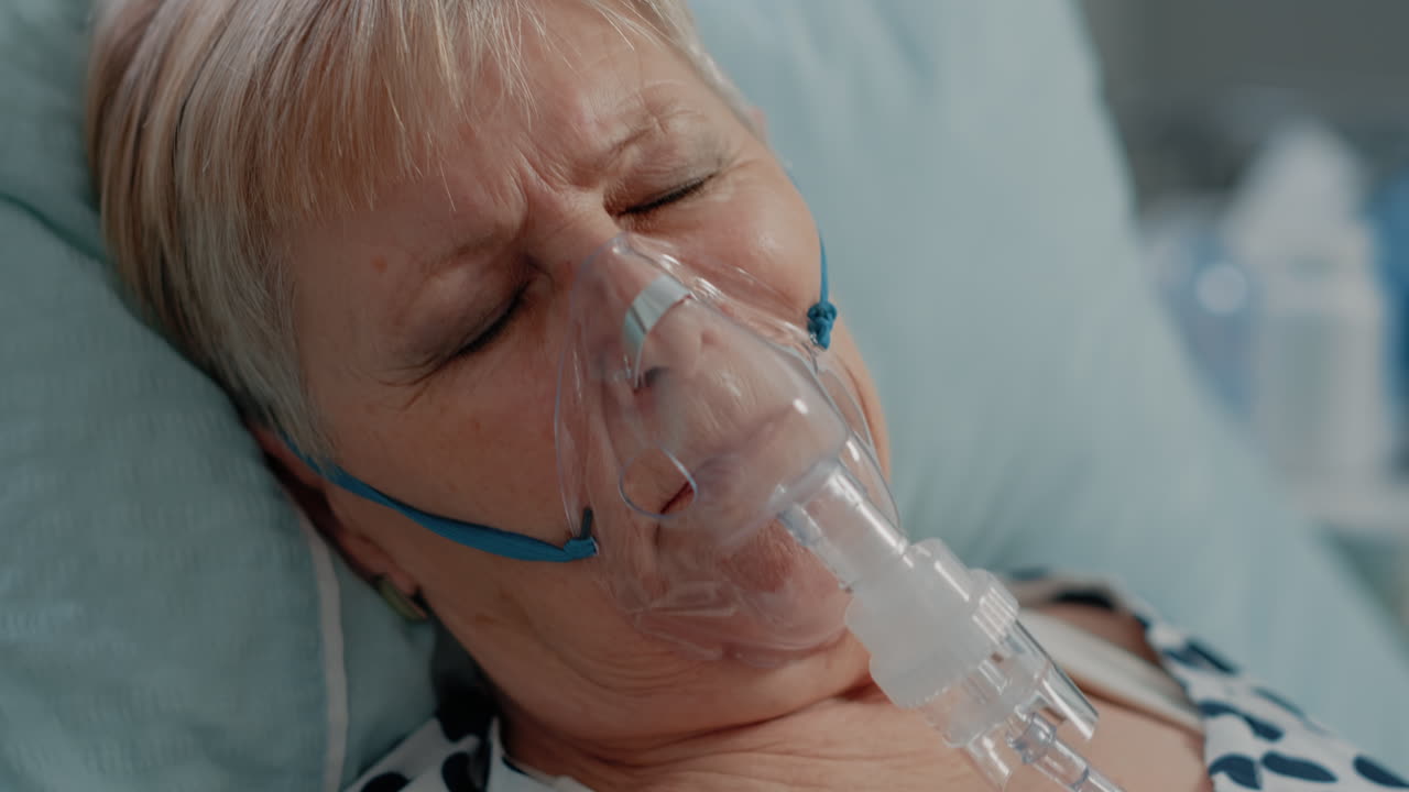 Close up of elder patient with oxygen mask laying in bed