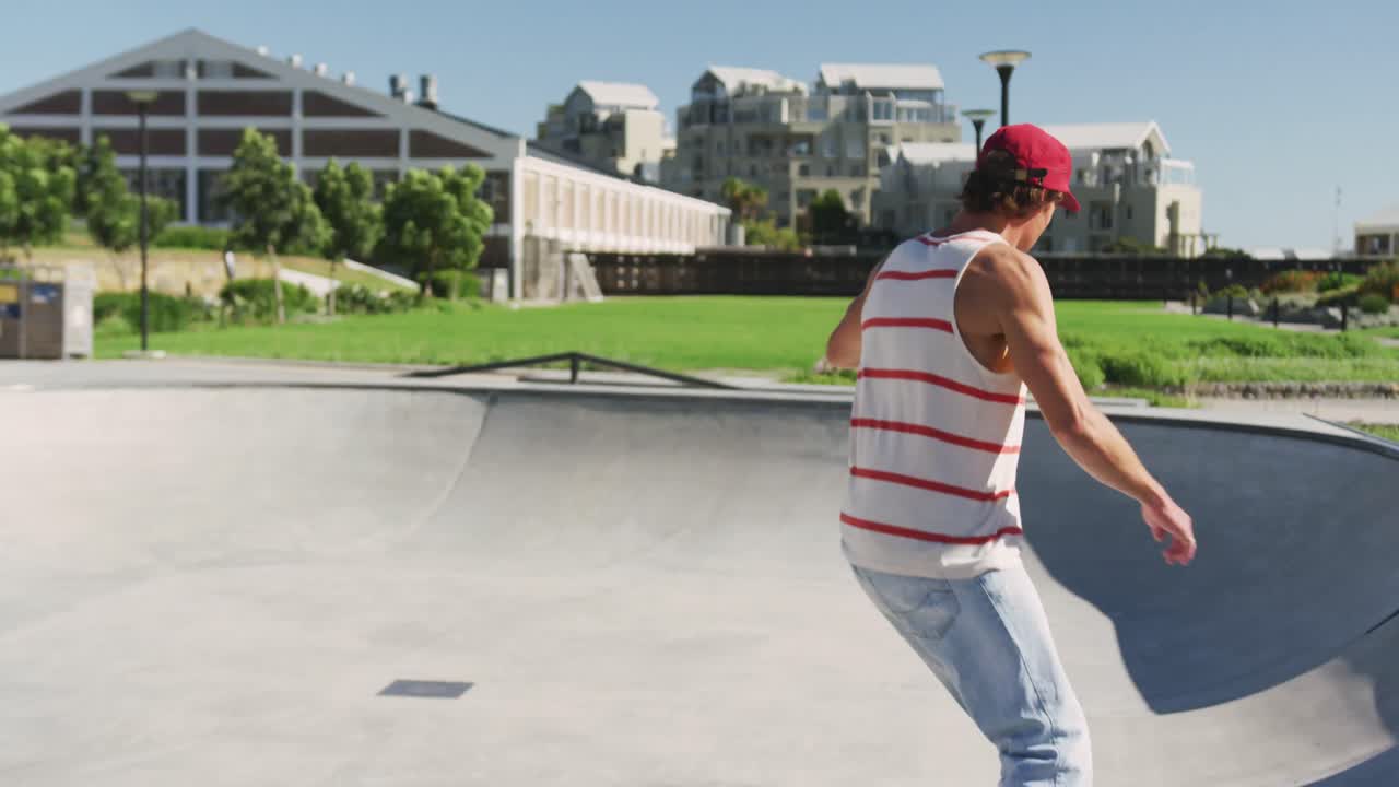 Uomo caucasico che va e salta sullo skateboard in una giornata di sole