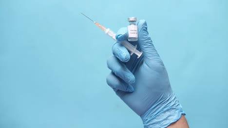 hand in gloves holding covid-19 vaccine syringe