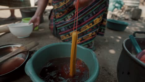 woman soaking threads into basin with dye for mayan textiles