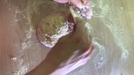 top-down shot of female hands making dough for bread with a plastic cleaning card at home