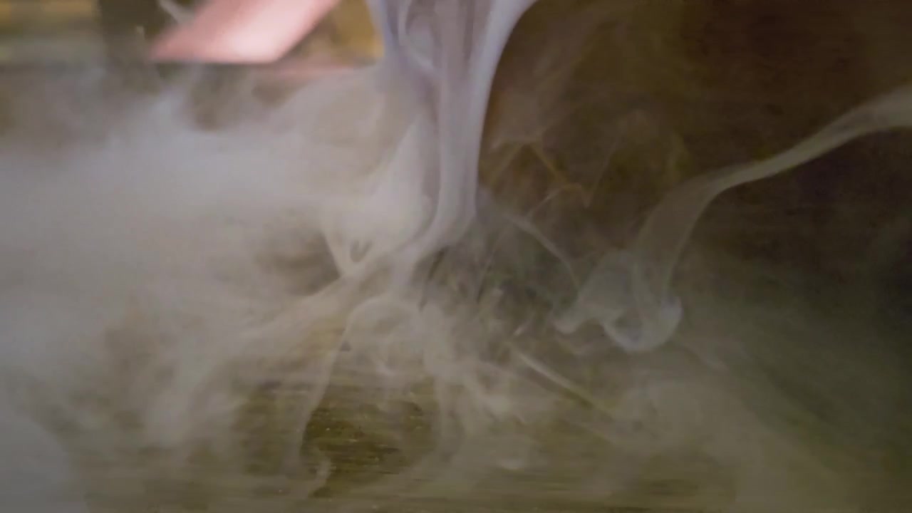 Milky white vapor or ink spreading through dark liquid, creating delicate wisps, cloudy turbulence, and abstract slow motion texture for cinematic backgrounds, overlays, or transitions.
