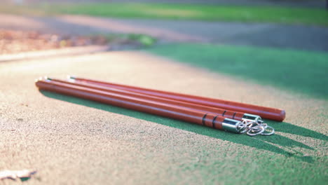 Arma-Nunchaku-En-El-Suelo-Con-Luz-Solar