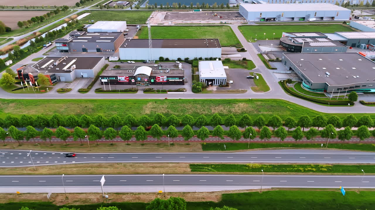 Industrial area with open green spaces. Aerial view of an industrial area with buildings, green lawns, and a busy road, highlighting urban and nature blend