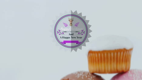 animation of christmas greetings on tag over cupcakes on white background
