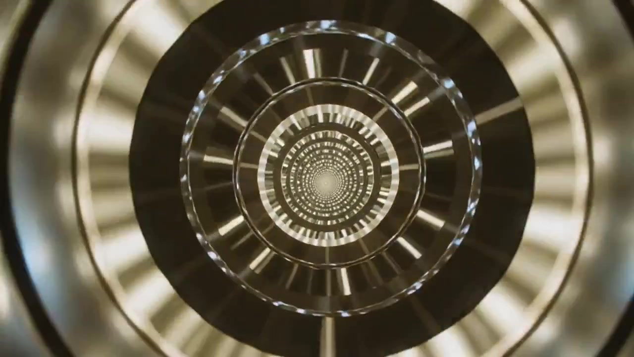 Anelli concentrici rotanti che cambiano colore dopo un cambio di illuminazione nel tunnel, suggerendo un movimento in avanti.