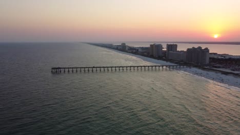 aerial view of a pier on a beach at sunset