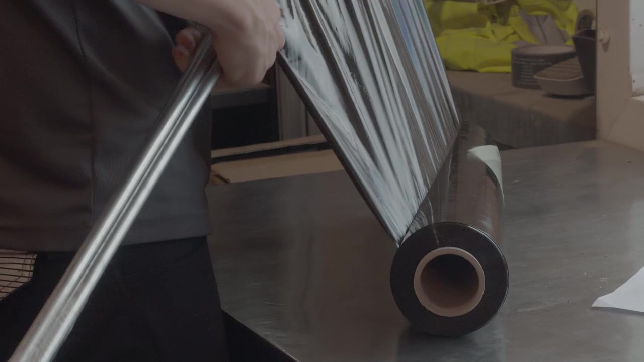 Operaio che avvolge barre di metallo per l'imballaggio industriale prima della spedizione a un cliente. Adatto per temi di produzione, consegna e magazzino, ripresa a mano.